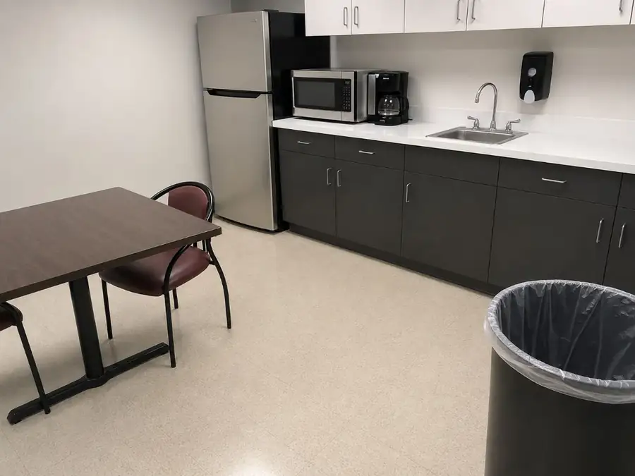 Same break room after professional cleaning — spotless counters and fresh trash liner